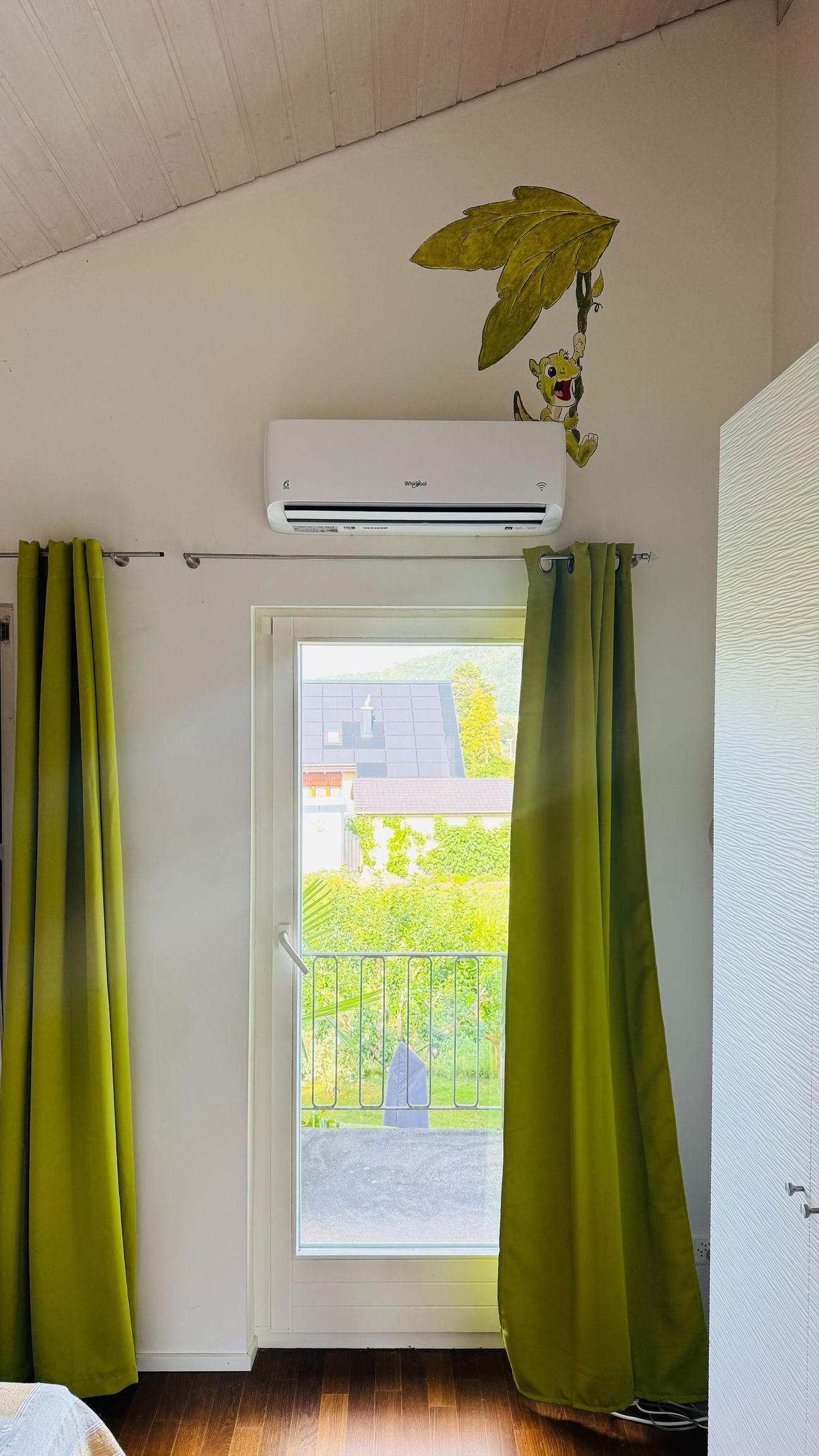 Wand-Klimagerät über einem Fenster mit grünen Vorhängen